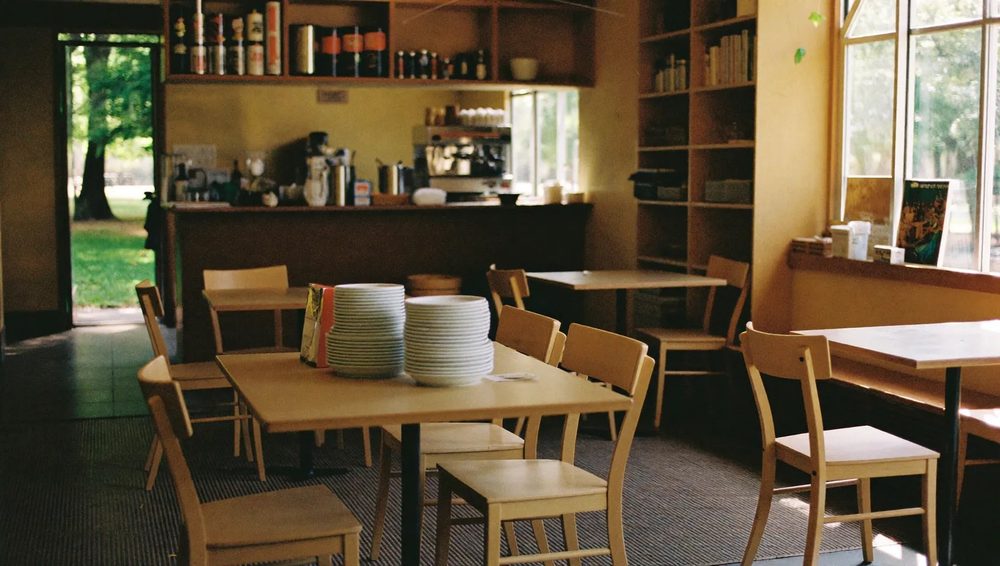The cafe room, with wooden tables set beneath tall windows